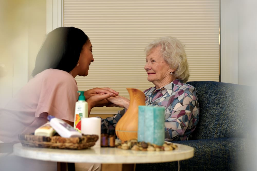Caregiver moisturizing senior woman's hands