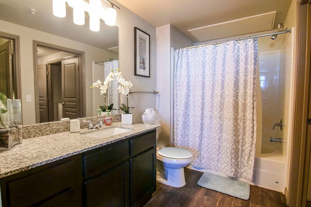 Granite countertop and a large vanity mirror in a model home's bathroom at Anatole on Briarwood in Midland, Texas