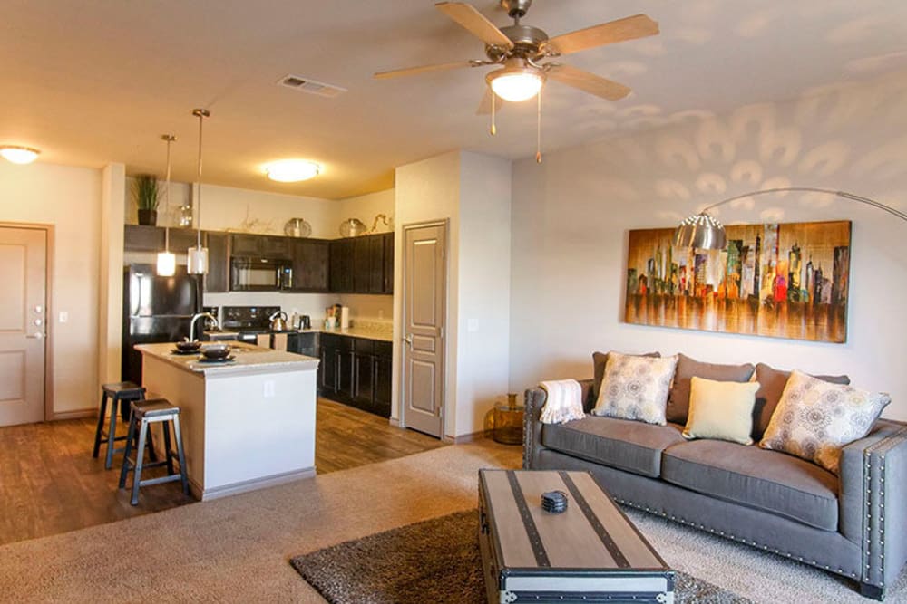 Open-concept living area with a ceiling fan and plush carpeting in a model home at Anatole on Briarwood in Midland, Texas