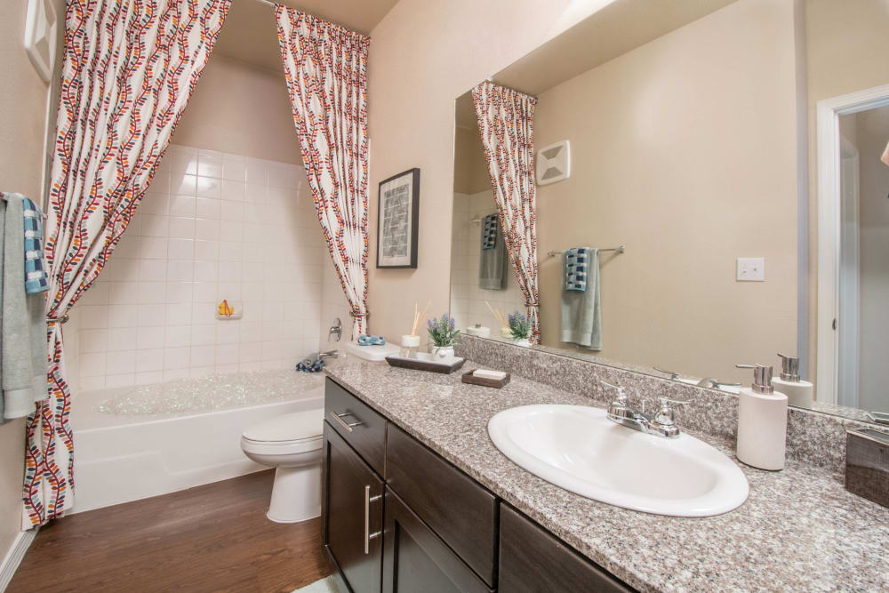Large vanity mirror and tiled shower in a model home's bathroom at Carrington Oaks in Buda, Texas