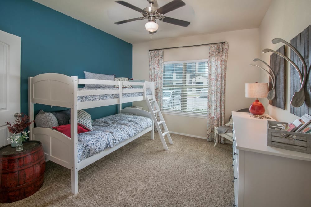 Plush carpeting and a ceiling fan in a model home's child's room at Carrington Oaks in Buda, Texas