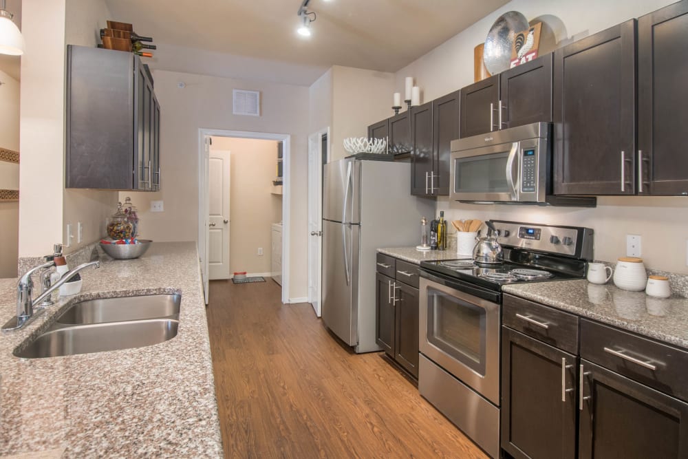 Hardwood flooring and granite countertops in a model home's kitchen at Carrington Oaks in Buda, Texas