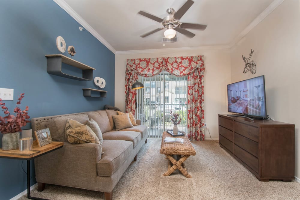 Plush carpeting and a ceiling fan in the living area of a model apartment at Carrington Oaks in Buda, Texas
