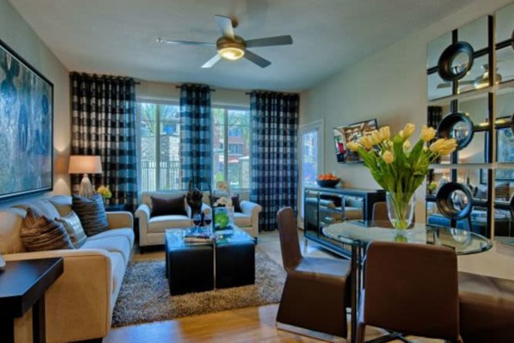 Draped windows and a ceiling fan in the well-furnished living space of a model apartment at Elevation Chandler in Chandler, Arizona