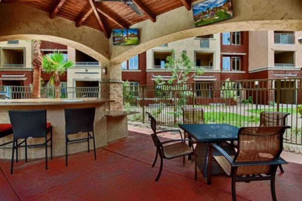 Covered outdoor lounge with bar seating and flatscreen TVs at Elevation Chandler in Chandler, Arizona
