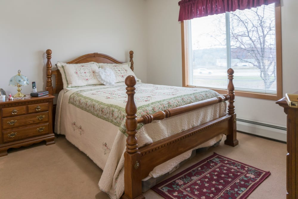 Resident bedroom with a side table at Meadow Lakes Senior Living in Rochester, Minnesota.