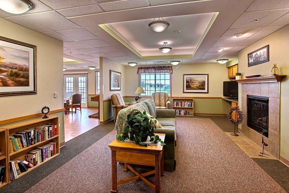 Resident lounge with books and fireplace at Milestone Senior Living Hillsboro in Hillsboro, Wisconsin.