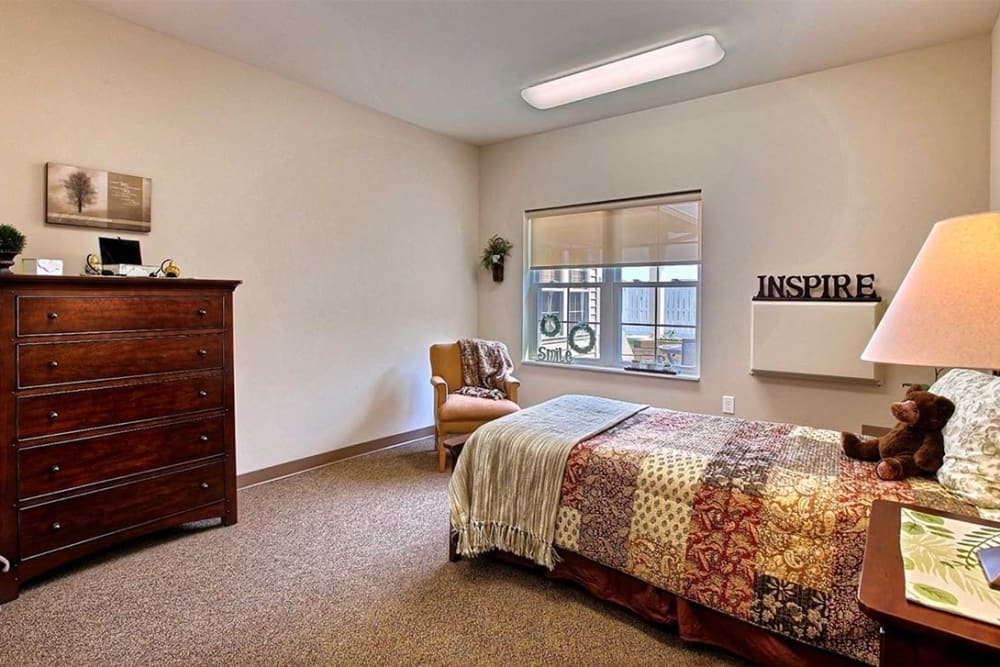 Resident bedroom with large dresser and bedside table at Milestone Senior Living Hillsboro in Hillsboro, Wisconsin