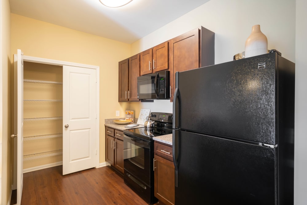 Sleek black appliances and a pantry in a model home's kitchen at Legends at White Oak in Ooltewah, Tennessee