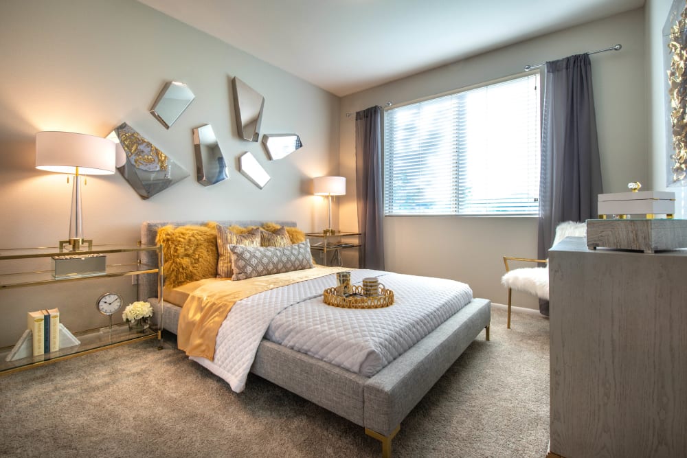 Plush carpeting and draped windows in the primary bedroom of a model home at Olympus at Daybreak in South Jordan, Utah