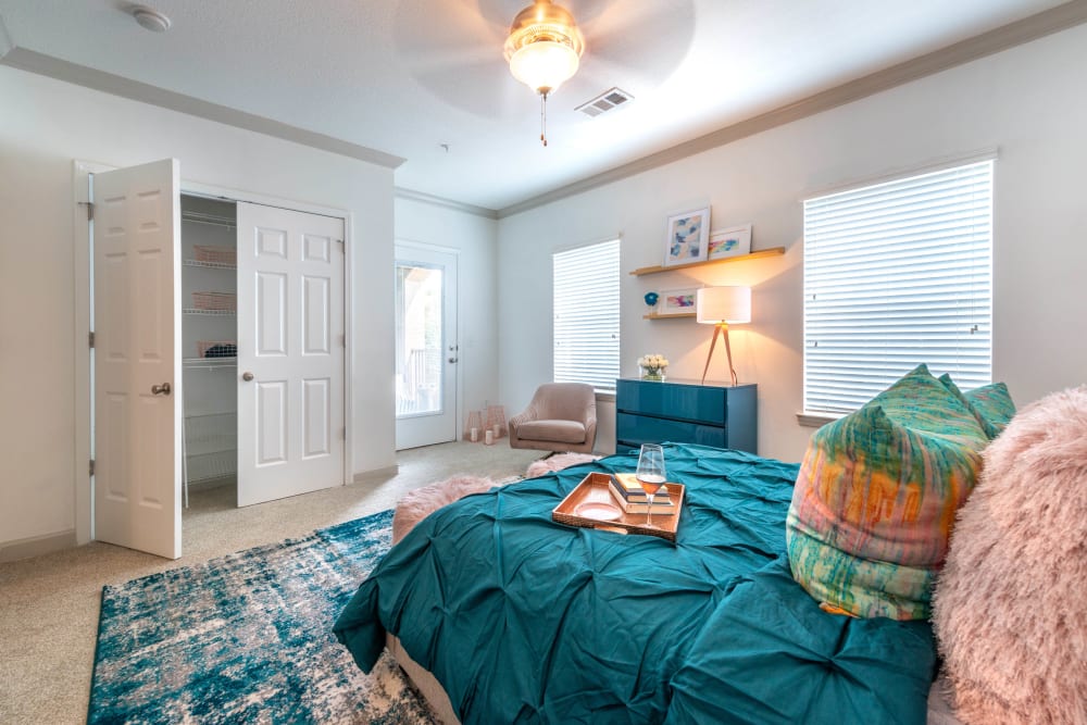 Walk-in closet and large bay windows in a model apartment's primary bedroom at Olympus Carrington in Pooler, Georgia