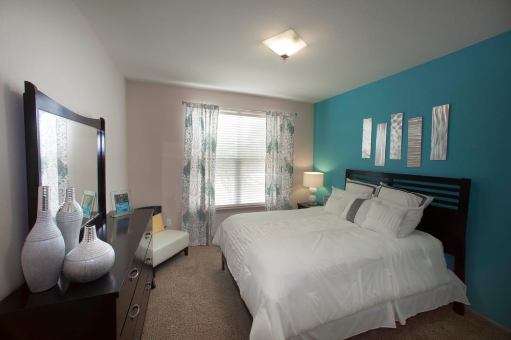 Draped windows and plush carpeting in a model home's bedroom at Olympus Katy Ranch in Katy, Texas