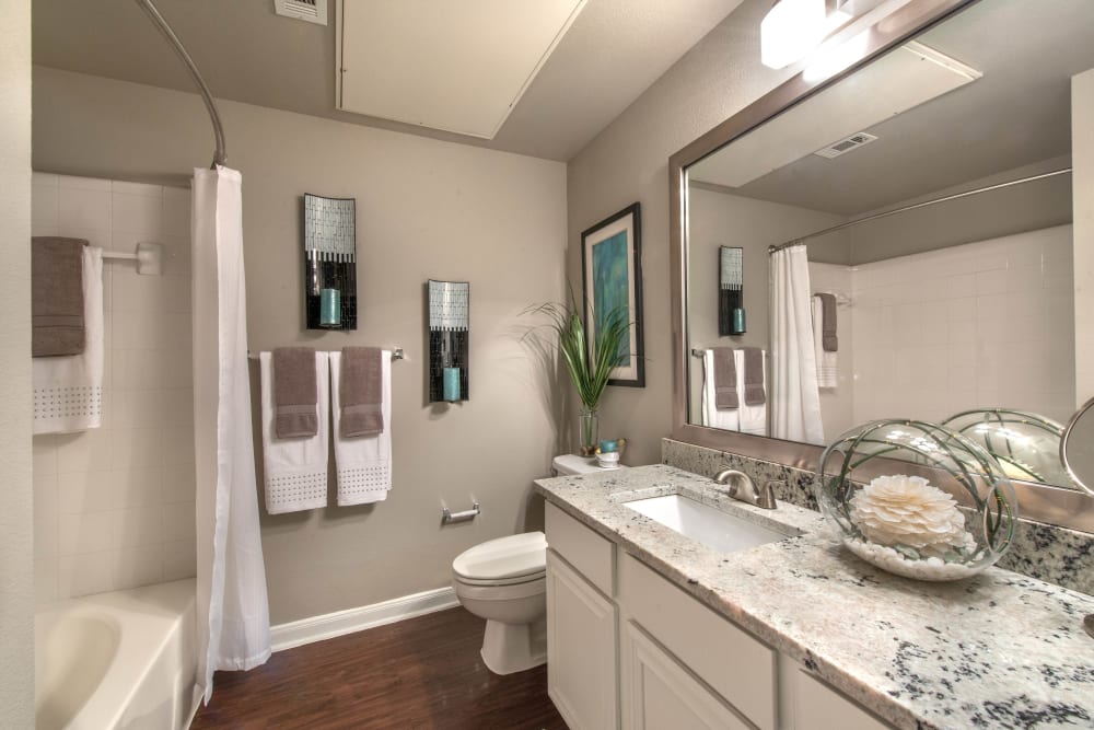 Ample counter space and hardwood flooring in a model home's bathroom at Olympus Las Colinas in Irving, Texas