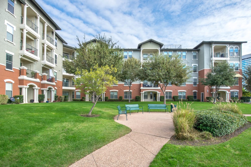 Walkway amid well-maintained lawns outside resident buildings at Olympus Las Colinas in Irving, Texas