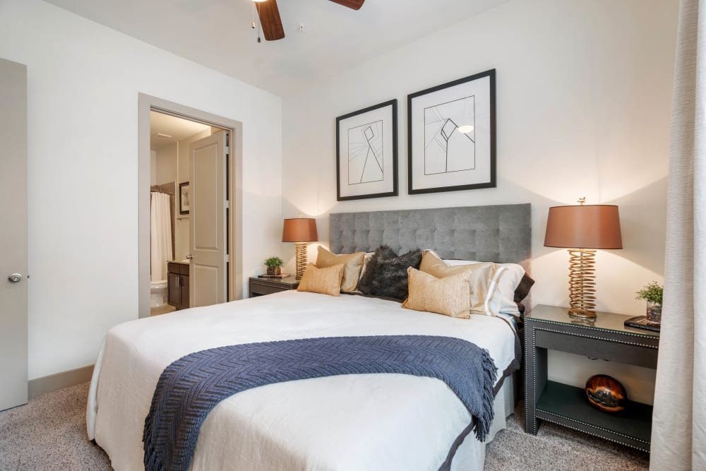 Well-furnished model home's primary bedroom with a ceiling fan and plush carpeting at Olympus Sierra Pines in The Woodlands, Texas