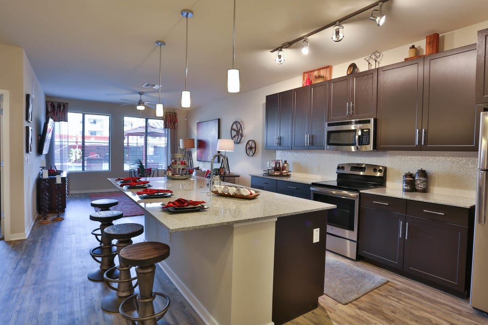 Model home's open-concept kitchen with stainless-steel appliances and granite countertops at Olympus Steelyard in Chandler, Arizona