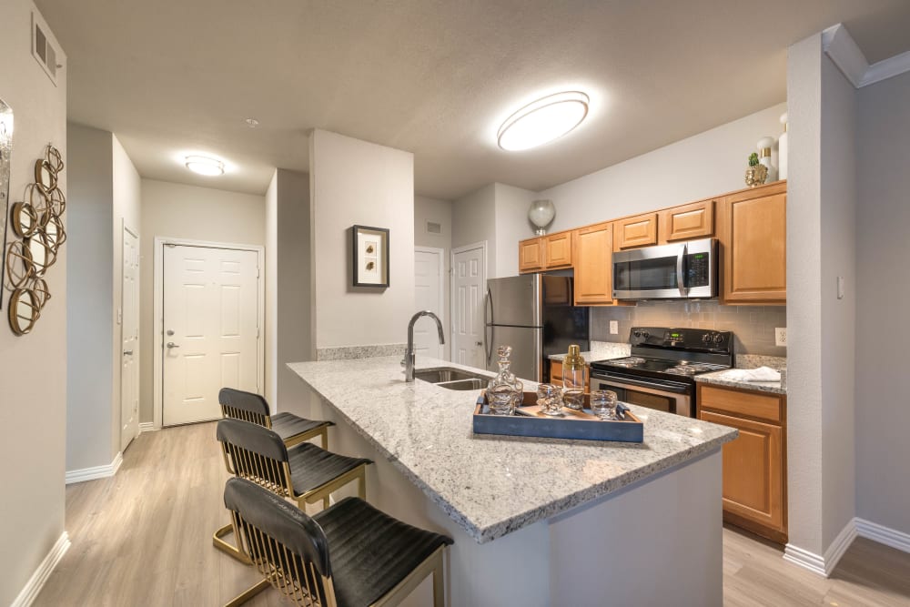 Model home's gourmet kitchen with an island and granite countertops at Olympus Stone Glen in Keller, Texas
