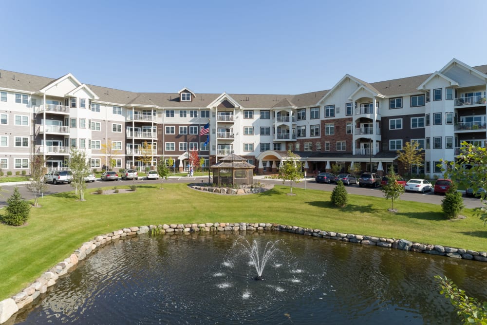 Exterior view of main building and a pond at Applewood Pointe of Roseville at Central Park in Roseville, Minnesota. 