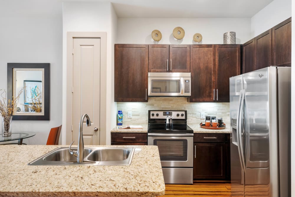 Gourmet kitchen with rich, dark wood cabinetry in a model apartment at Olympus Sierra Pines in The Woodlands, Texas