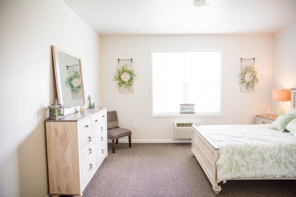 Comfortable bedroom with dresser and large window at Arcadian Cove in Richmond, Kentucky.