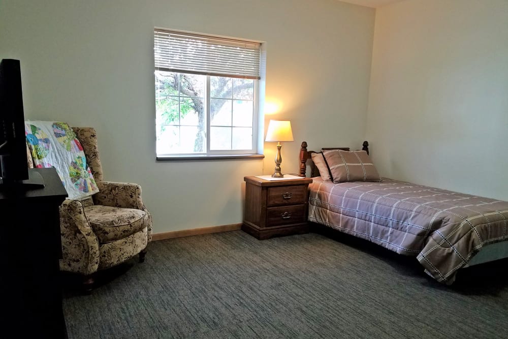 Studio apartment with bed and chair at Clover Ridge Place in Maquoketa, Iowa.