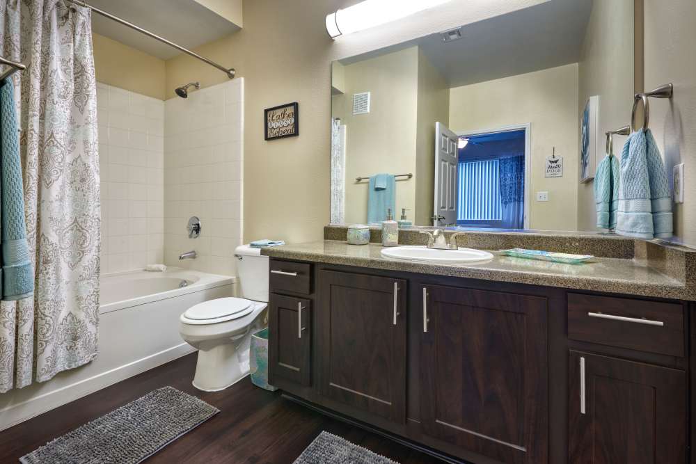 Spacious bathroom with tub and brown cabinets at Hawthorne Hill Apartments in Thornton, Colorado