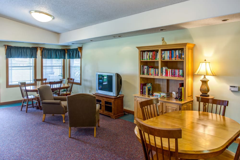 Bright community room with books and a TV at Prairie Hills Independence in Independence, Iowa.