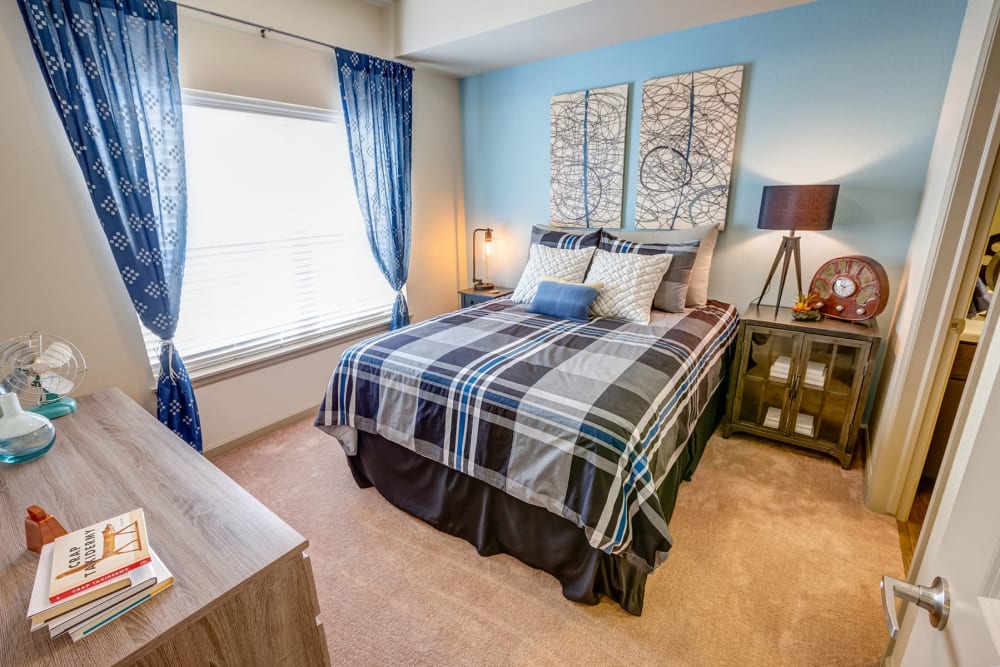 Plush carpeting and draped windows in the primary bedroom of a model apartment at Granite 550 in Casper, Wyoming