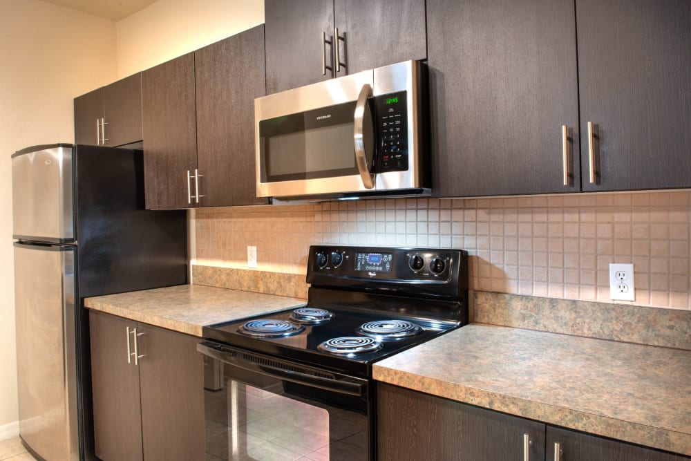 Modern kitchen with dark wood cabinetry in a model apartment at Mirador & Stovall at River City in Jacksonville, Florida
