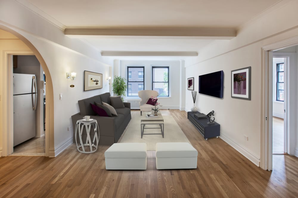 Large living room with wood-style flooring and windows at The Sutton Collection in New York, New York