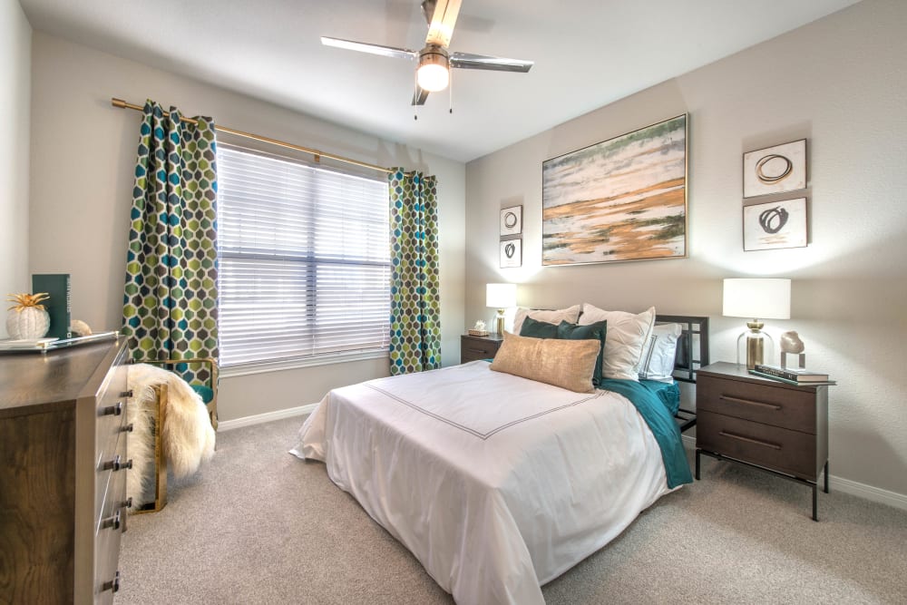 Plush carpeting and draped bay windows in a model home's bedroom at Olympus Town Center in Keller, Texas