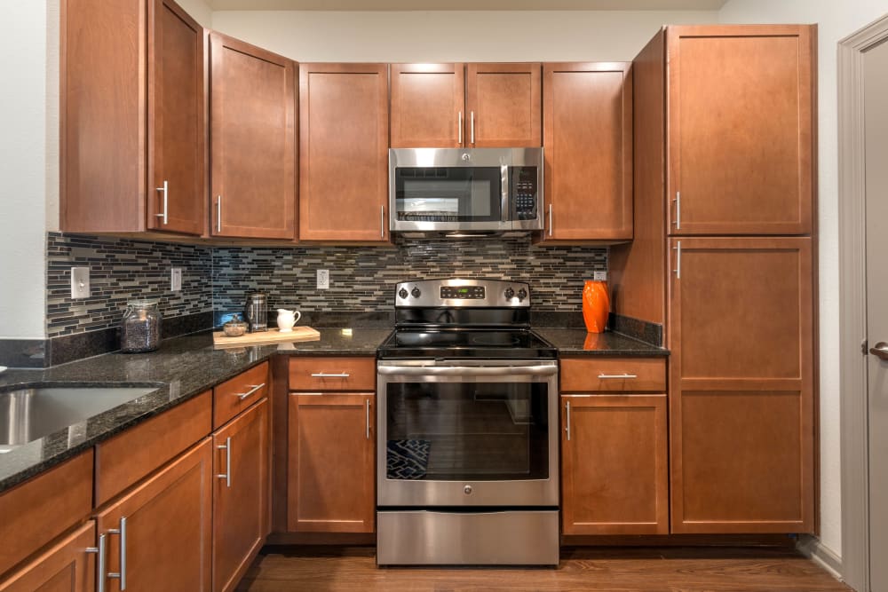 Cherry wood cabinetry and stainless-steel appliances in a model home's kitchen at Olympus Waterford in Keller, Texas