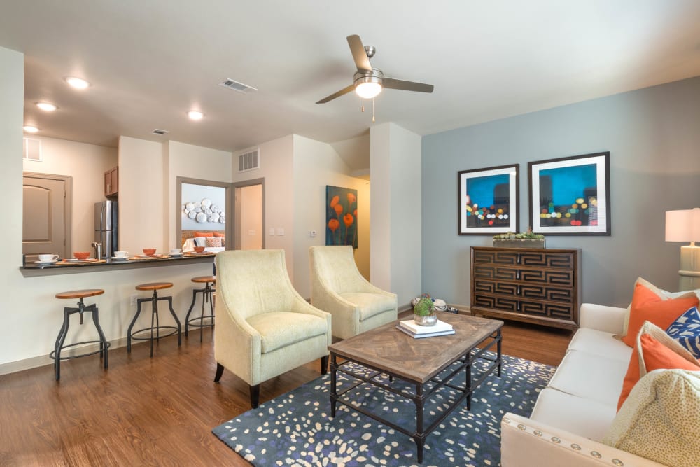 Well-furnished living area with a view of the kitchen's breakfast bar in a model home at Olympus Waterford in Keller, Texas