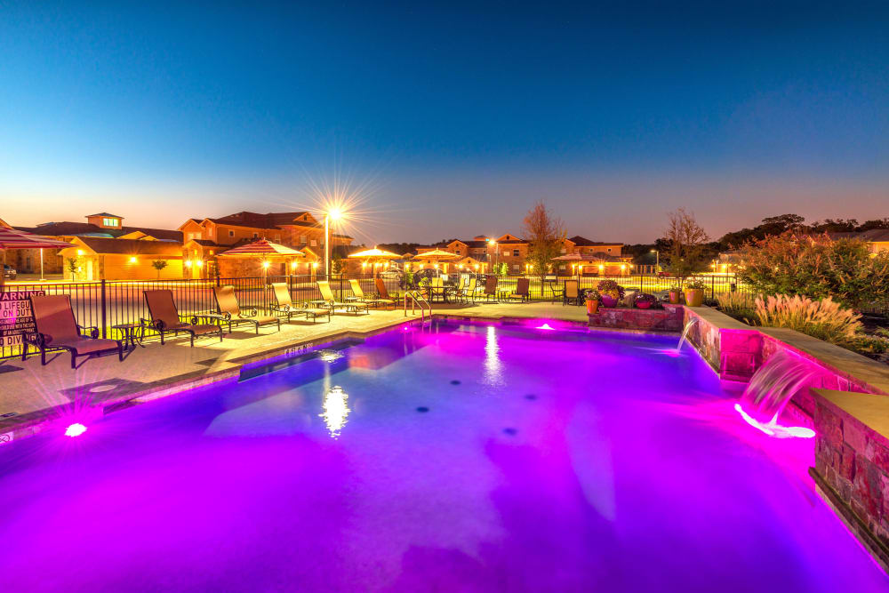 Purple underwater lights illuminating the pool at dusk at Olympus Willow Park in Willow Park, Texas