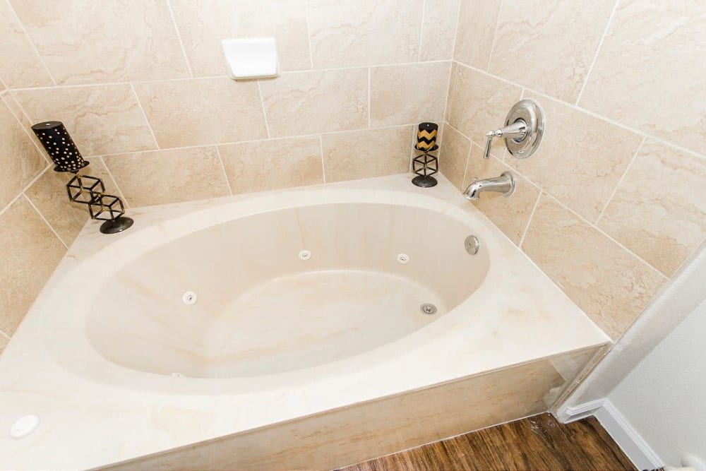 Tiled walls around the oval soaking tub in a model home's master bathroom at Olympus Woodbridge in Sachse, Texas