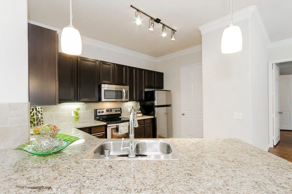 Expansive granite countertops in a model townhome's gourmet kitchen at Olympus Woodbridge in Sachse, Texas