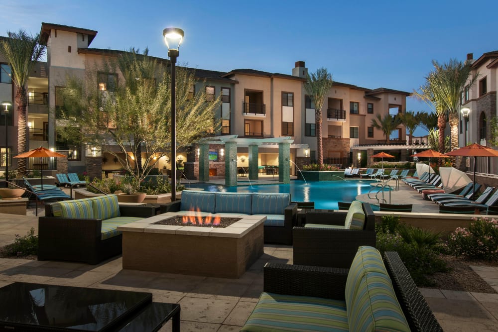 Resort-style swimming pool area and fire pit at dusk at Redstone at SanTan Village in Gilbert, Arizona