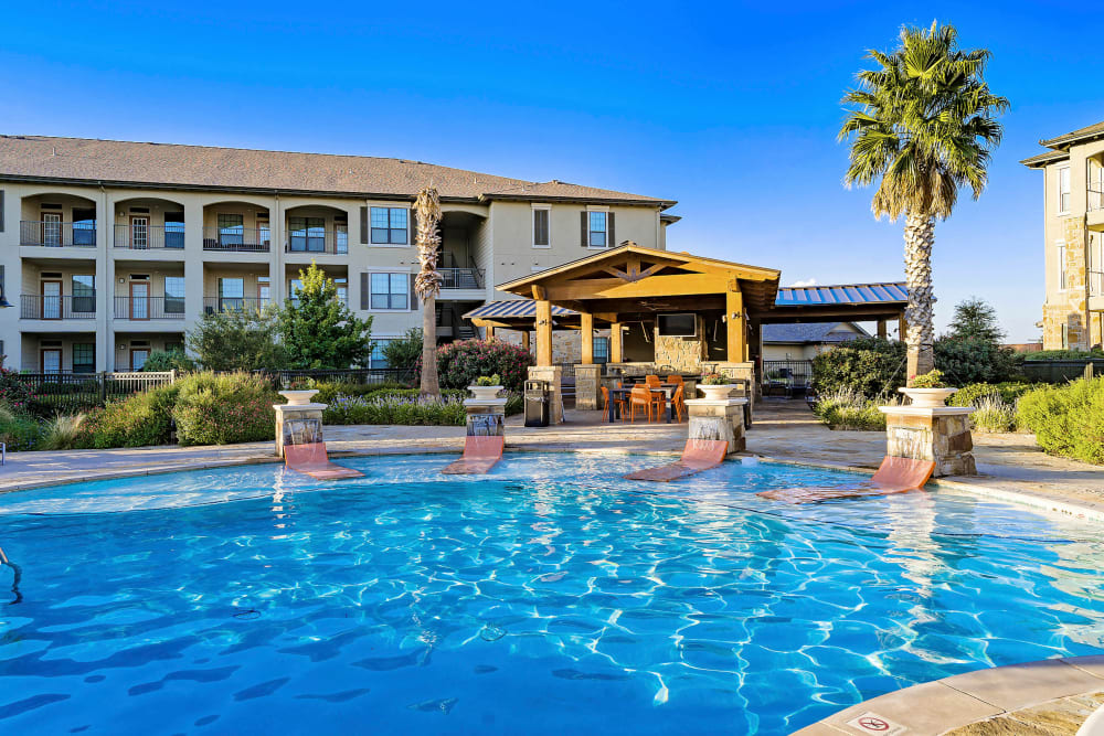 Resort-style swimming pool with lounge chairs in the sun deck at Sedona Ranch in Odessa, Texas