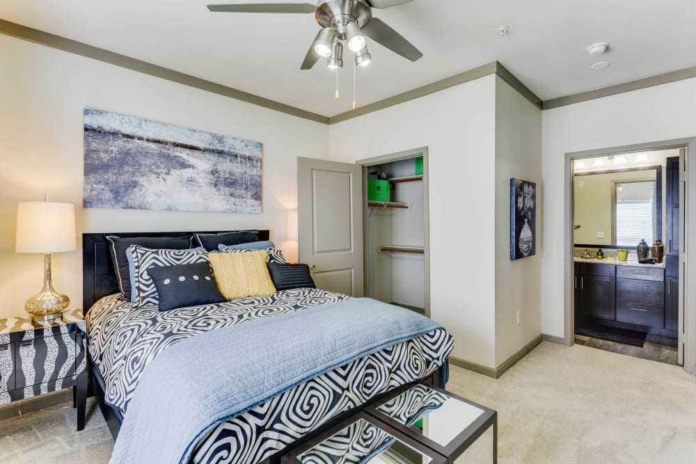 En suite bathroom and a ceiling fan in a model home's primary bedroom at Tacara at Westover Hills in San Antonio, Texas