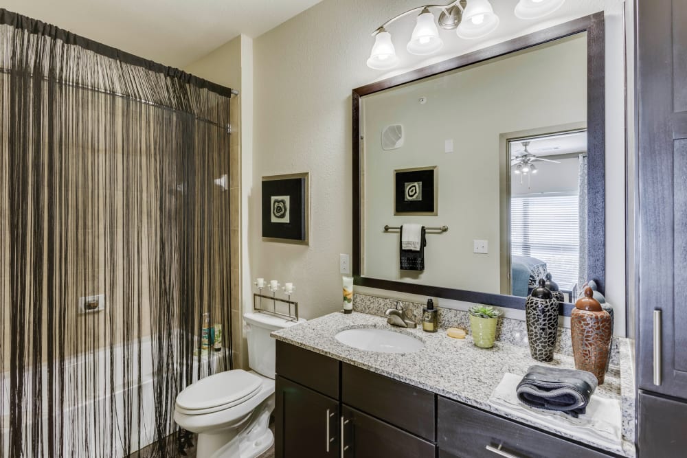 Large vanity mirror and a granite countertop in a model home's bathroom at Tacara at Westover Hills in San Antonio, Texas