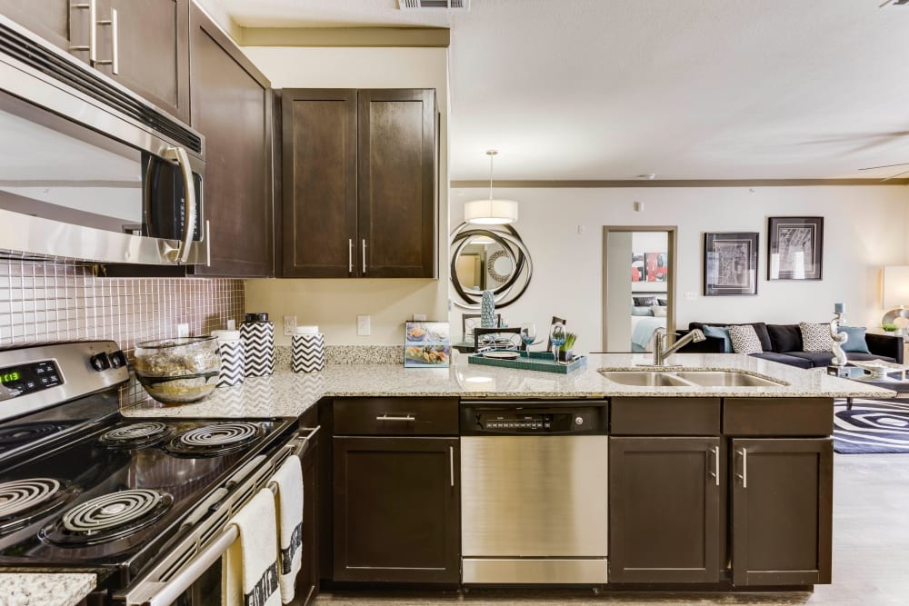 Dark wood cabinetry and granite countertops in a model apartment's gourmet kitchen at Tacara at Westover Hills in San Antonio, Texas