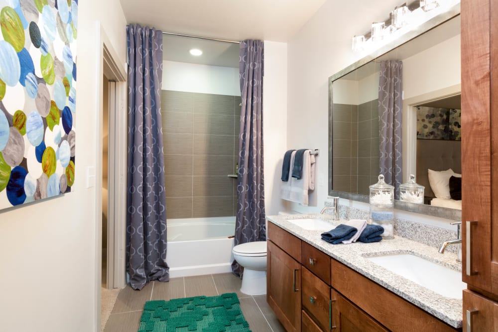 Custom tiled shower and a large vanity mirror in a model home's primary bathroom at The Davis in Fort Worth, Texas