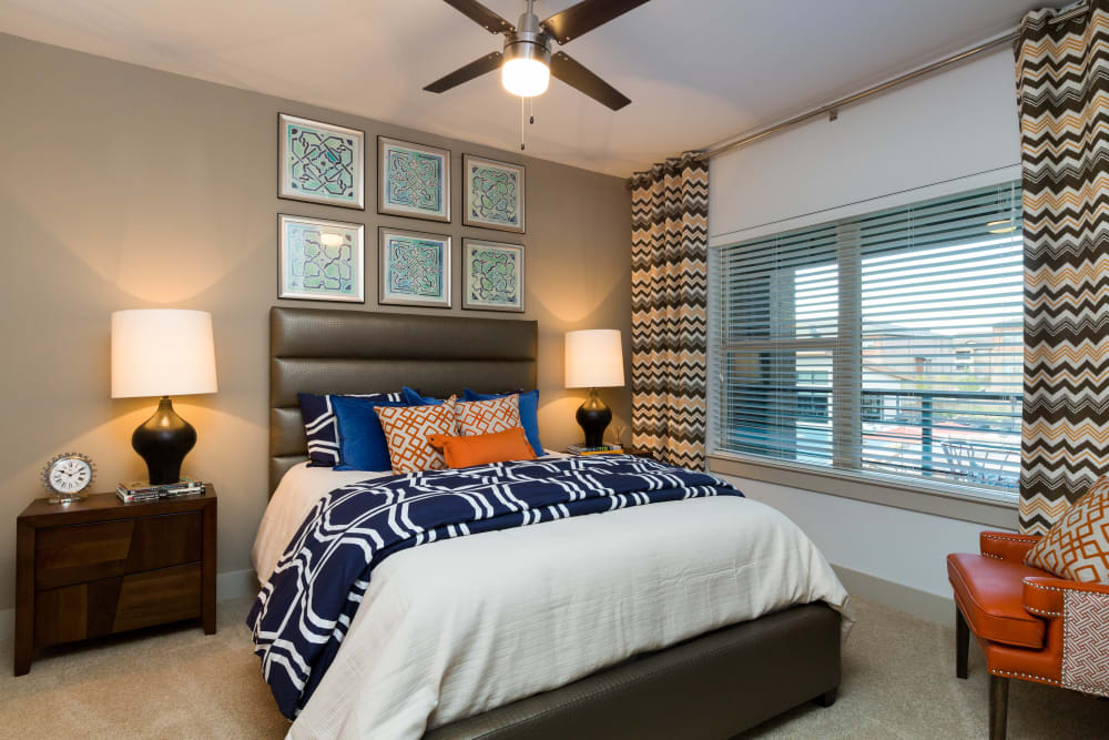 Well-furnished primary bedroom with a ceiling fan in a model home at The Davis in Fort Worth, Texas