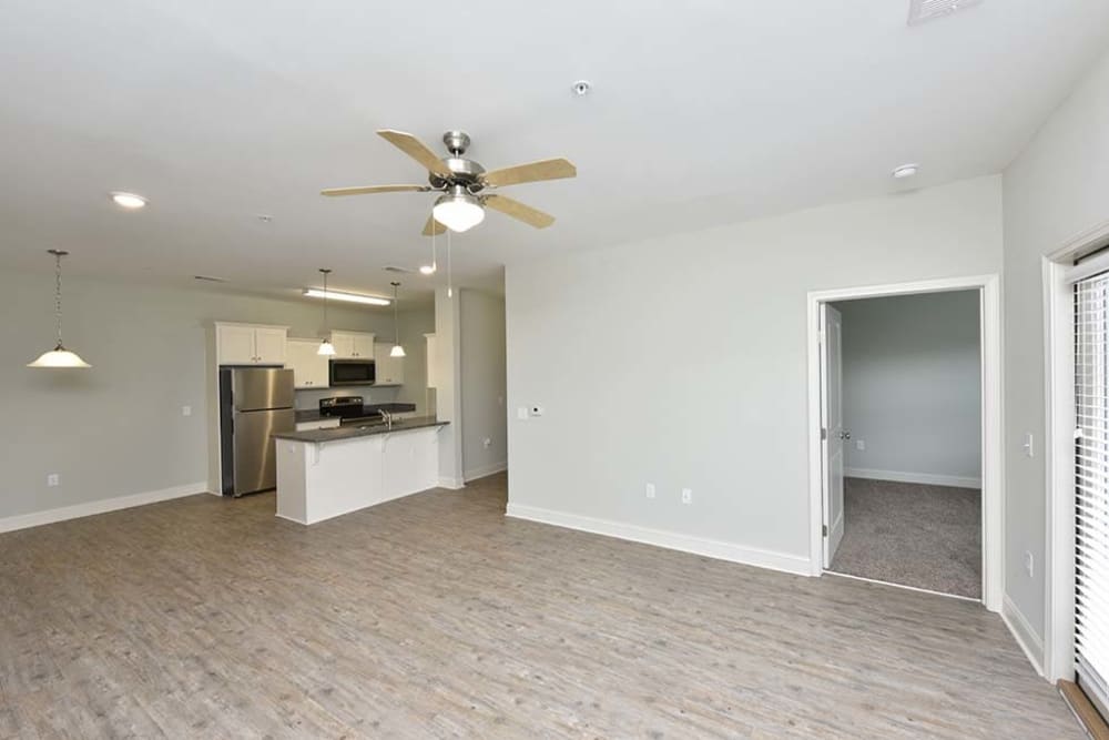 Large open-concept model home's living area with hardwood floors and a ceiling fan at The Enclave in Brunswick, Georgia