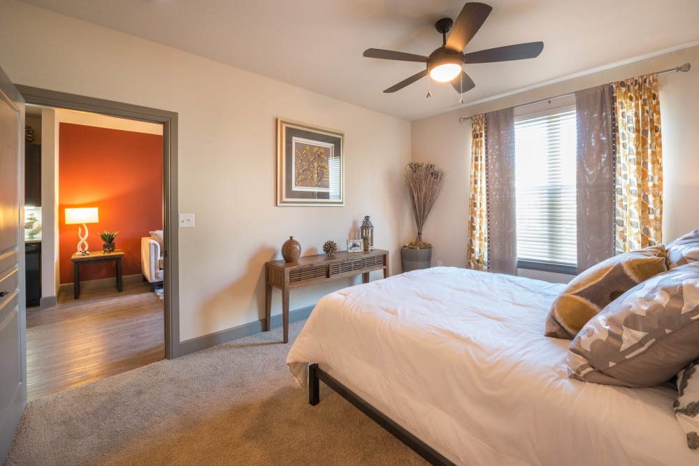 Model home's master bedroom with a ceiling fan and plush carpeting at Union At Carrollton Square in Carrollton, Texas