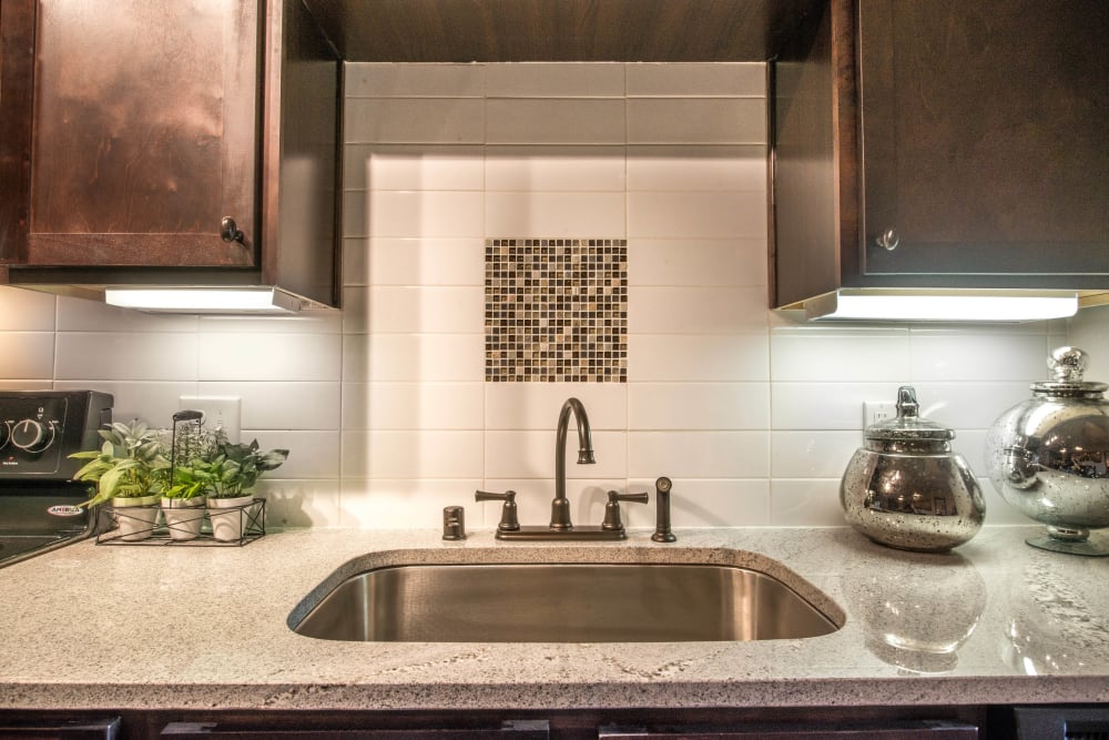 Custom tile backsplash and a recessed sink in a model apartment's gourmet kitchen at Union At Carrollton Square in Carrollton, Texas