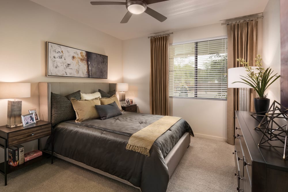 Well-furnished model home's bedroom with a ceiling fan at Vistara at SanTan Village in Gilbert, Arizona