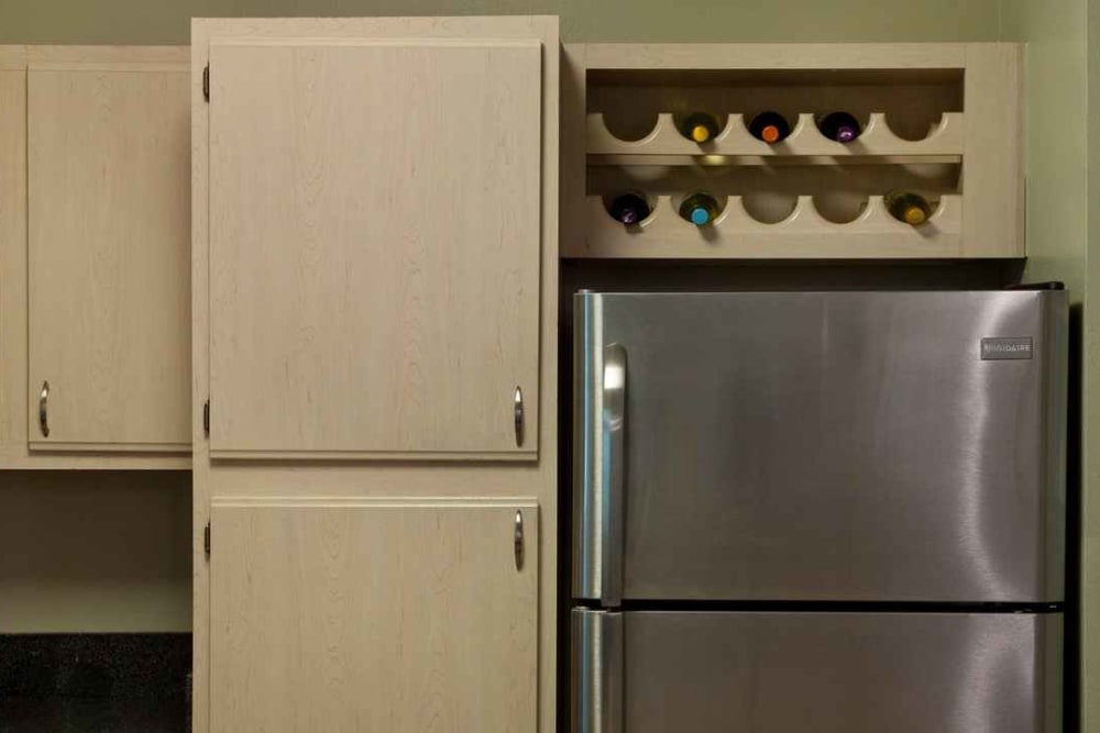Pantry cupboards and a built-in wine rack above the stainless-steel refrigerator in a model home at Wimberly at Deerwood in Jacksonville, Florida