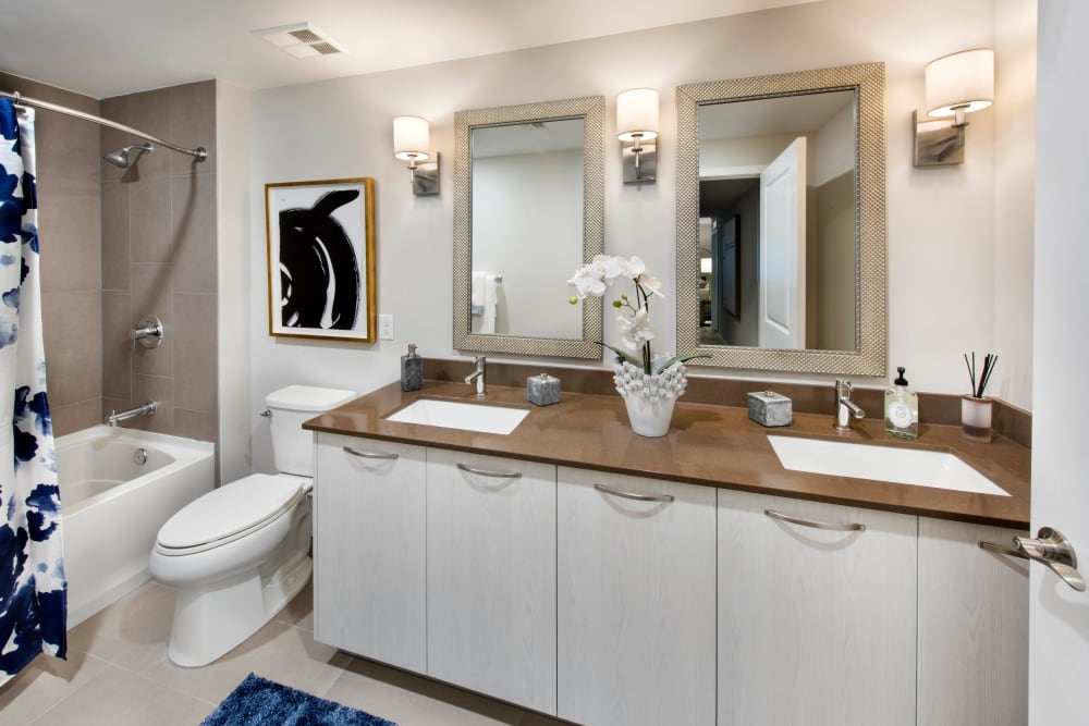 Dual sinks and individual vanity mirrors in a model home's primary bathroom at Olympus Harbour Island in Tampa, Florida