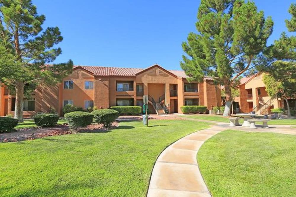 Mature trees and green grass along a walking path at Alterra Apartments in Las Vegas, Nevada